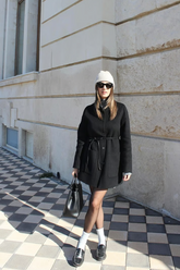 a lady wears a black wool coat with a string belt